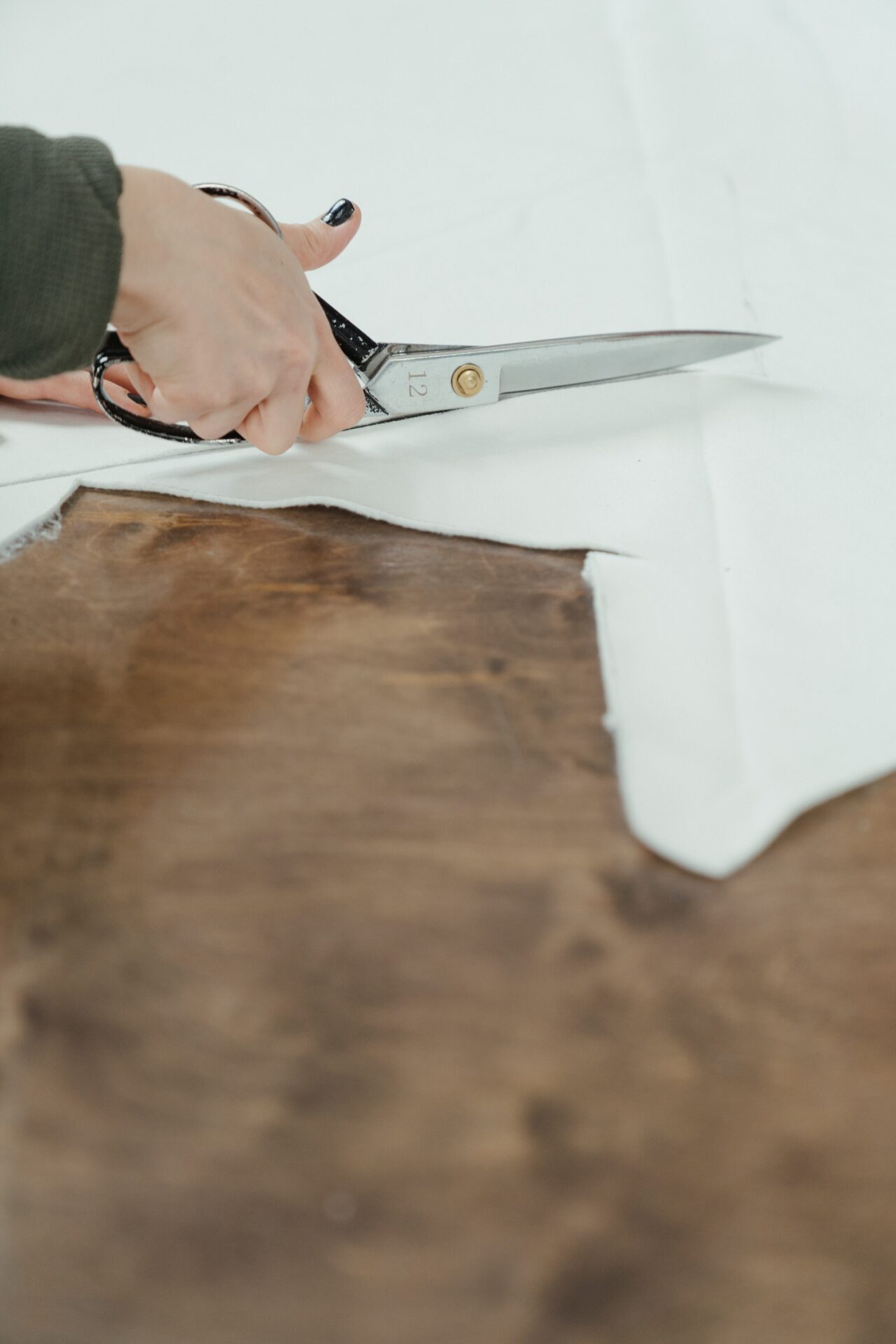 Hand cutting fabric with large scissors (Photo by cottonbro on Pexels)