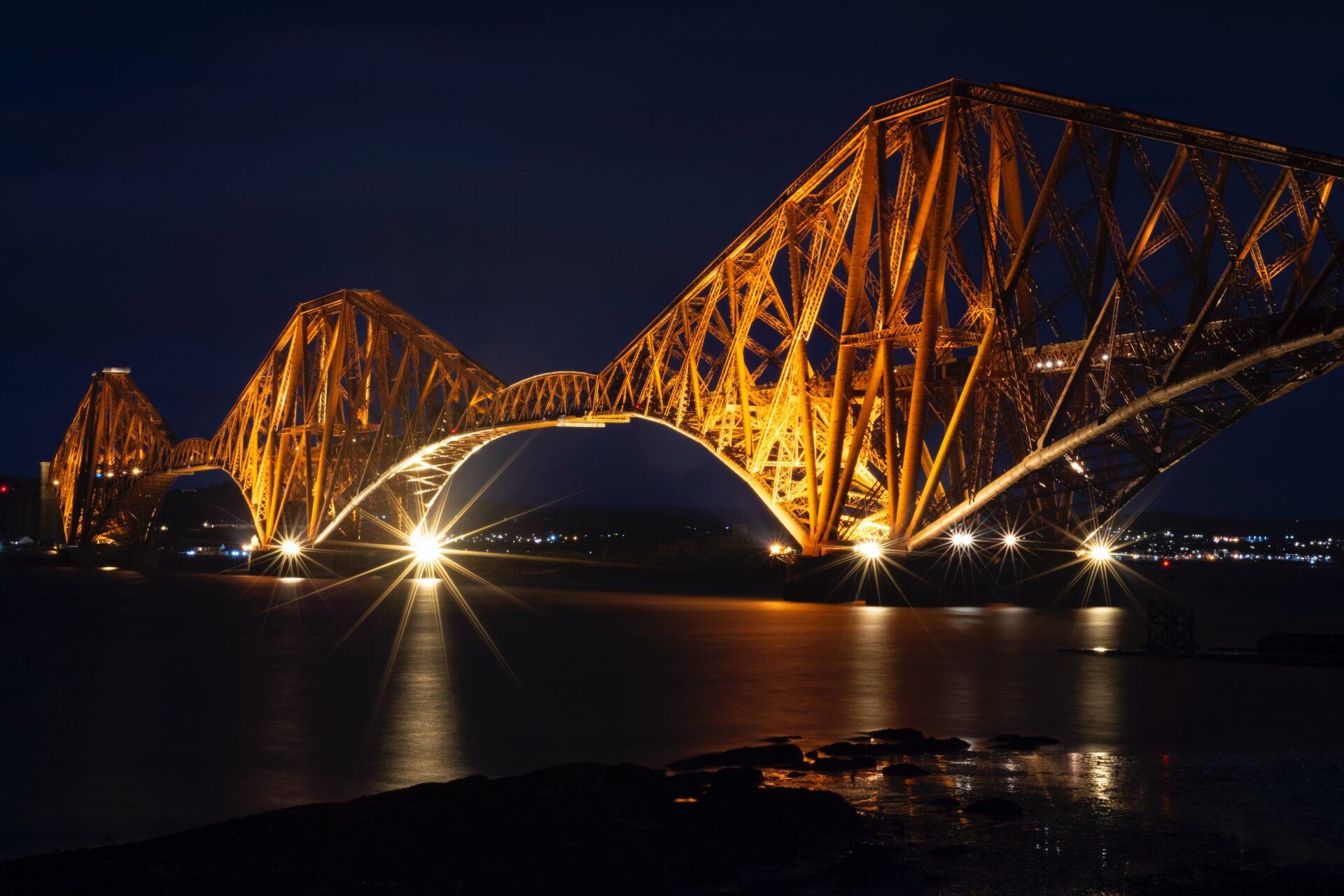 Edinburgh's Forth Rail Bridge lit at night (Photo by Gordon Robbie Hendry on Unsplash)