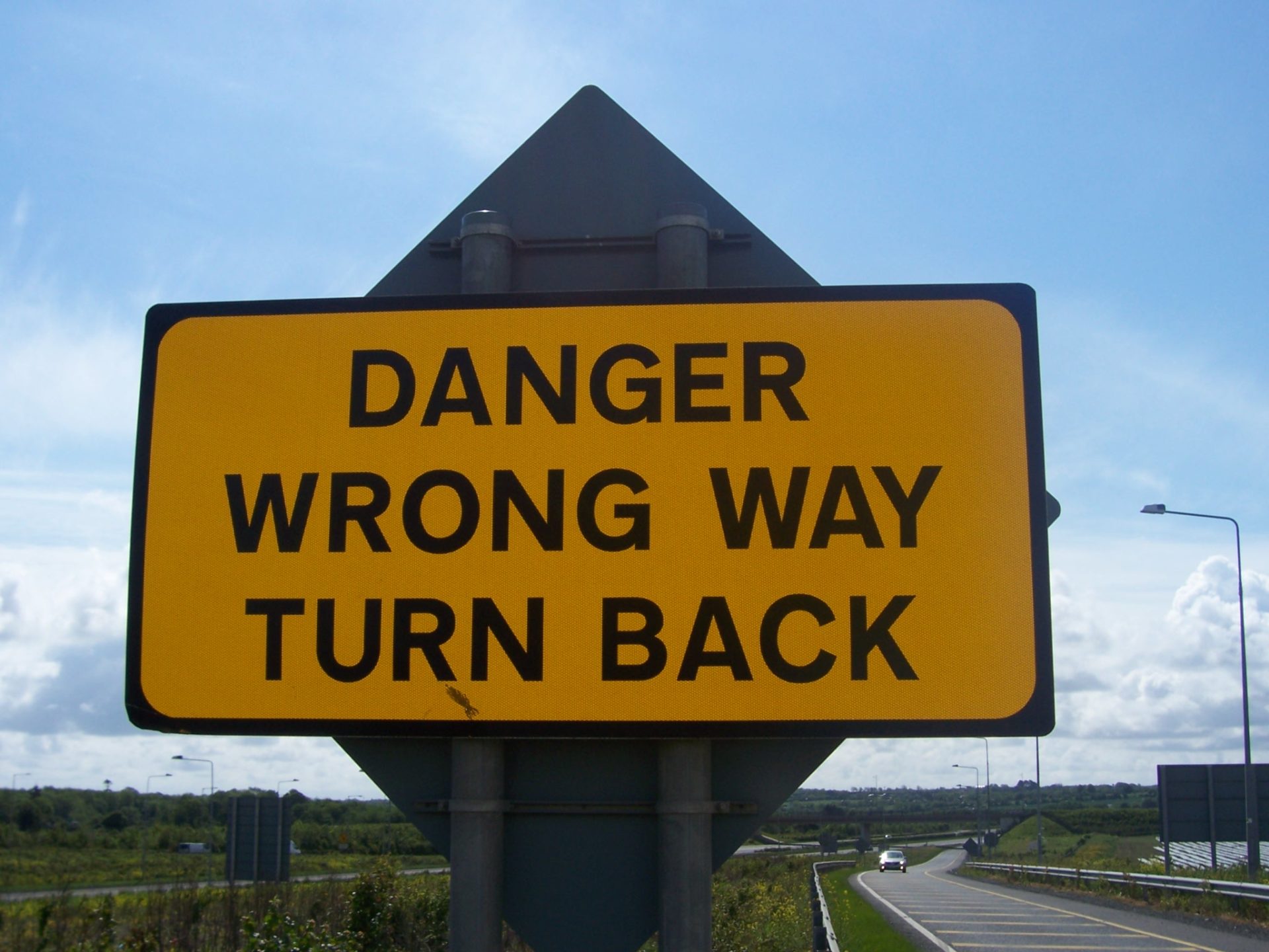 Sign saying "danger wrong way turn back"