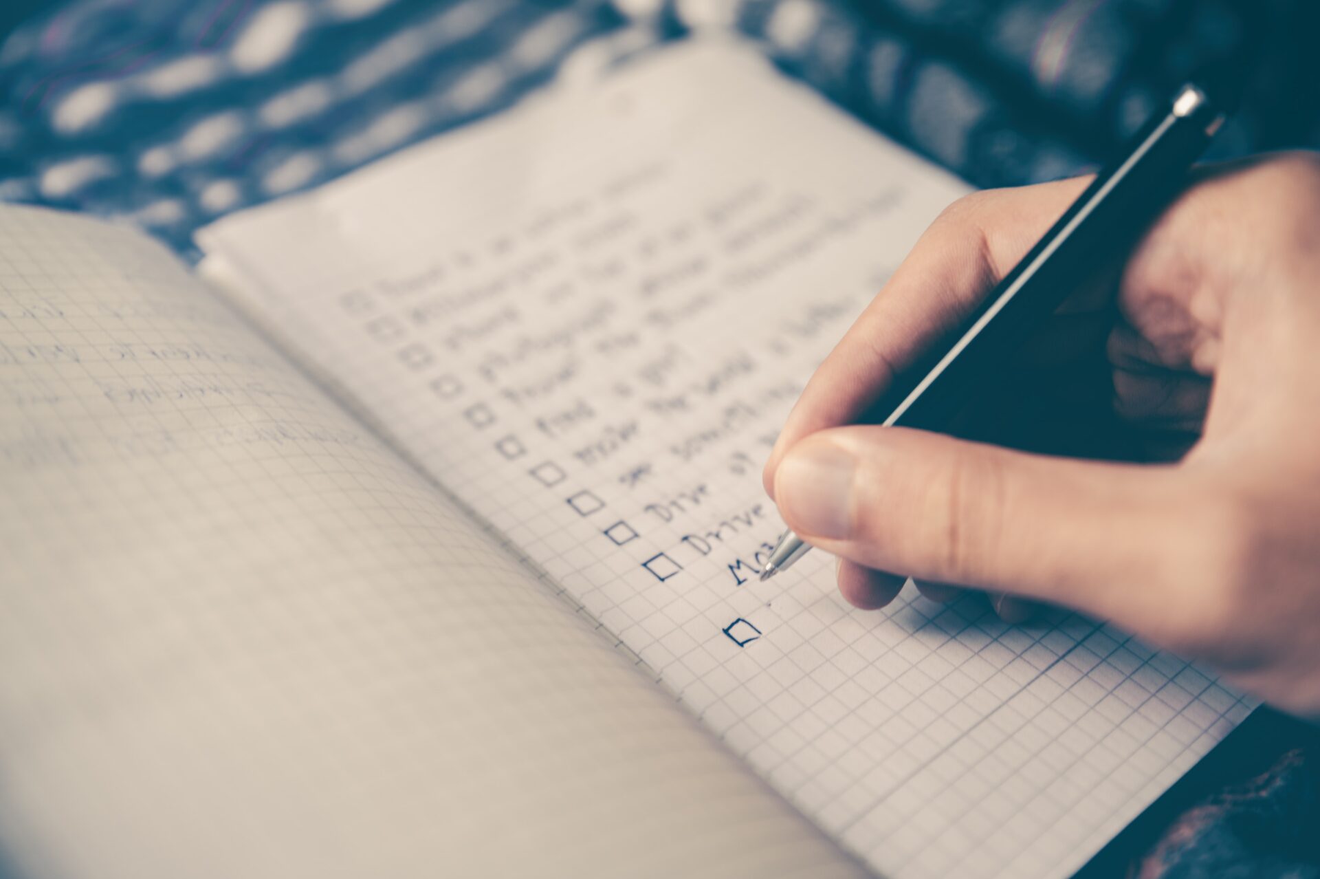 Person writing checklist into book with squared paper (Photo by Glenn Carstens-Peters on Unsplash)