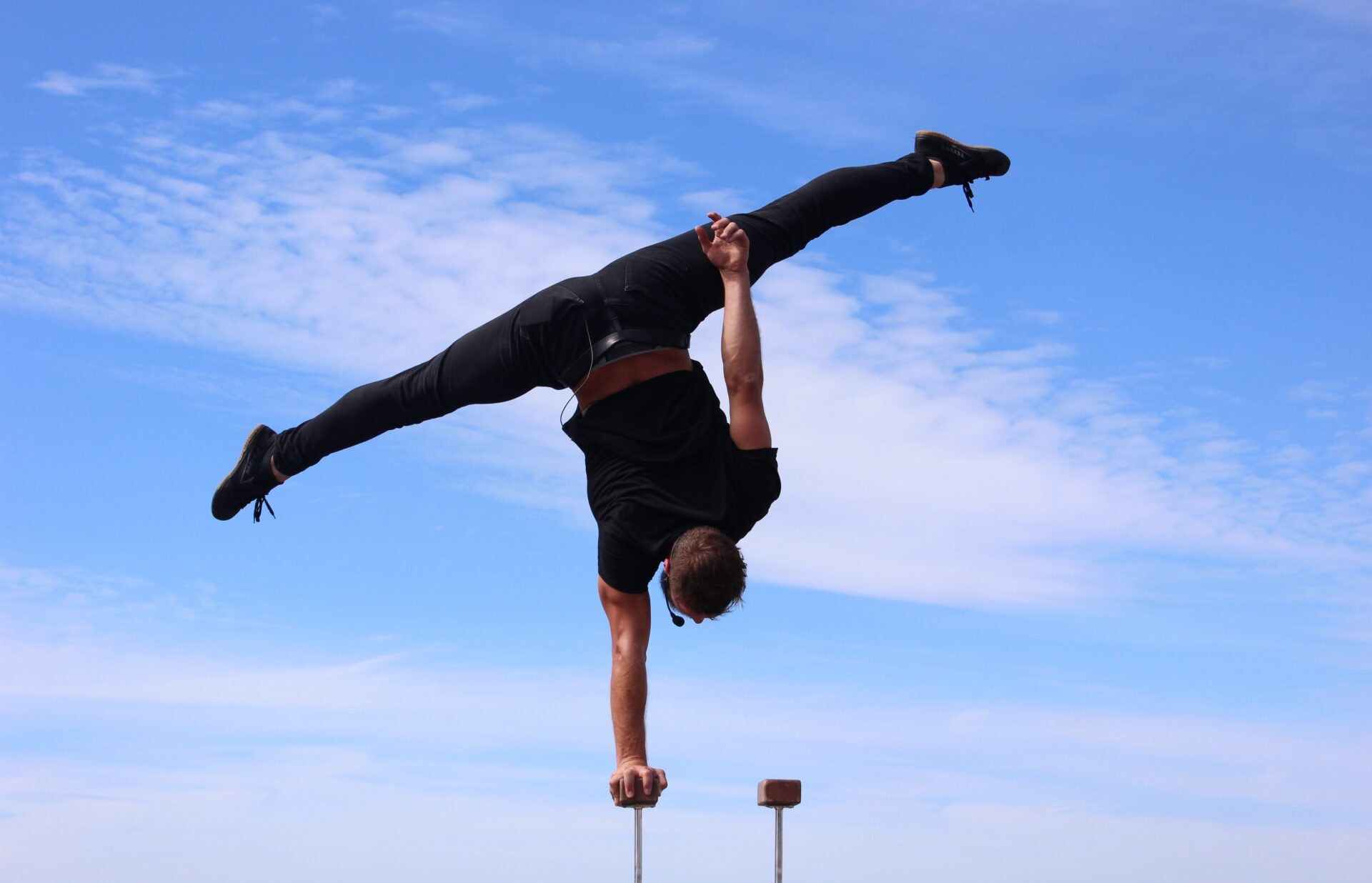 Man balancing upside-down in a one-handed handstand with legs doing the splits (Photo by Ian Flores on Unsplash)