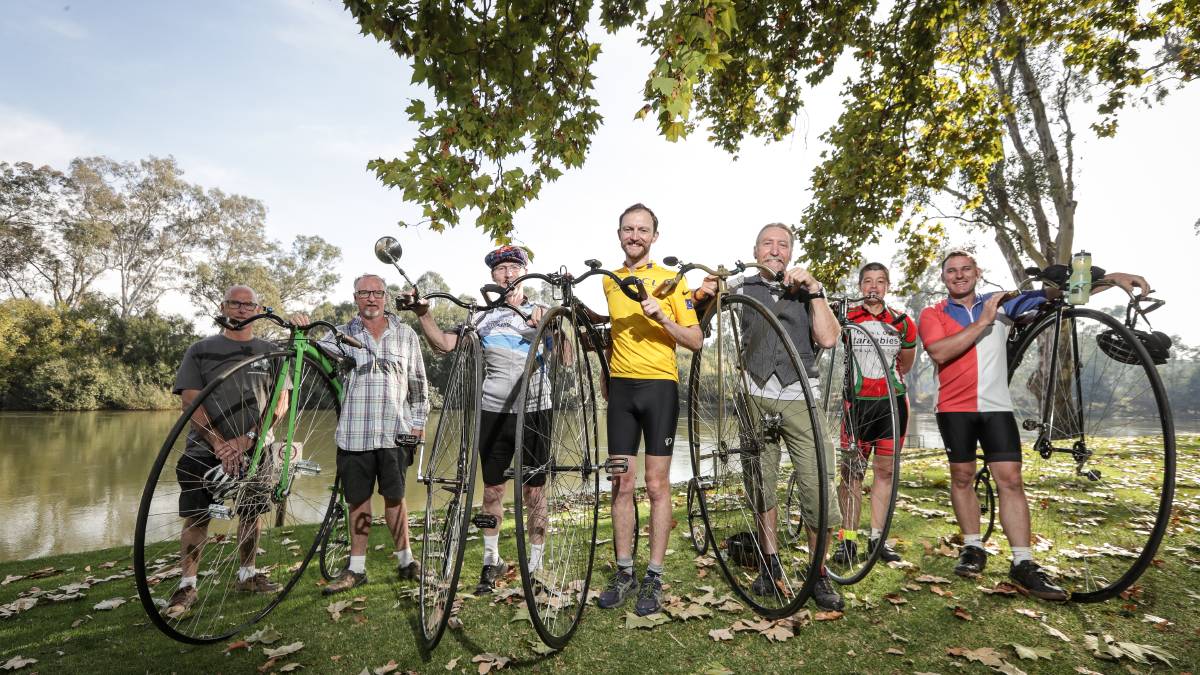 People in a row with their penny farthing bicycles