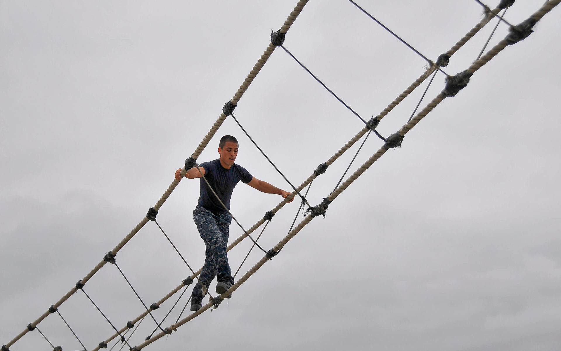 US Navy recruit crosses a rope bridge on an obstacle course (U.S. Navy photo by Mass Communication Specialist 2nd Daniel Barker/Released)