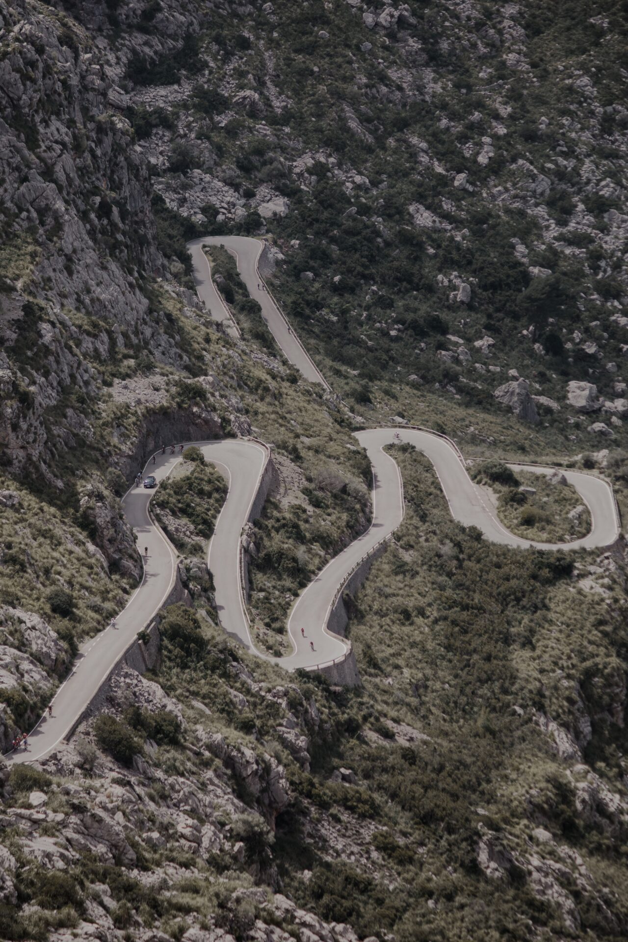Overhead photo of cyclists riding up a twisting mountain road (Photo by Nicklas from Pexels)