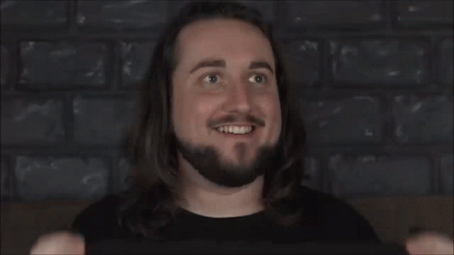 YouTuber Jim Caddick aka Caddicarus smiles while holding up an LED sign reading fuck off